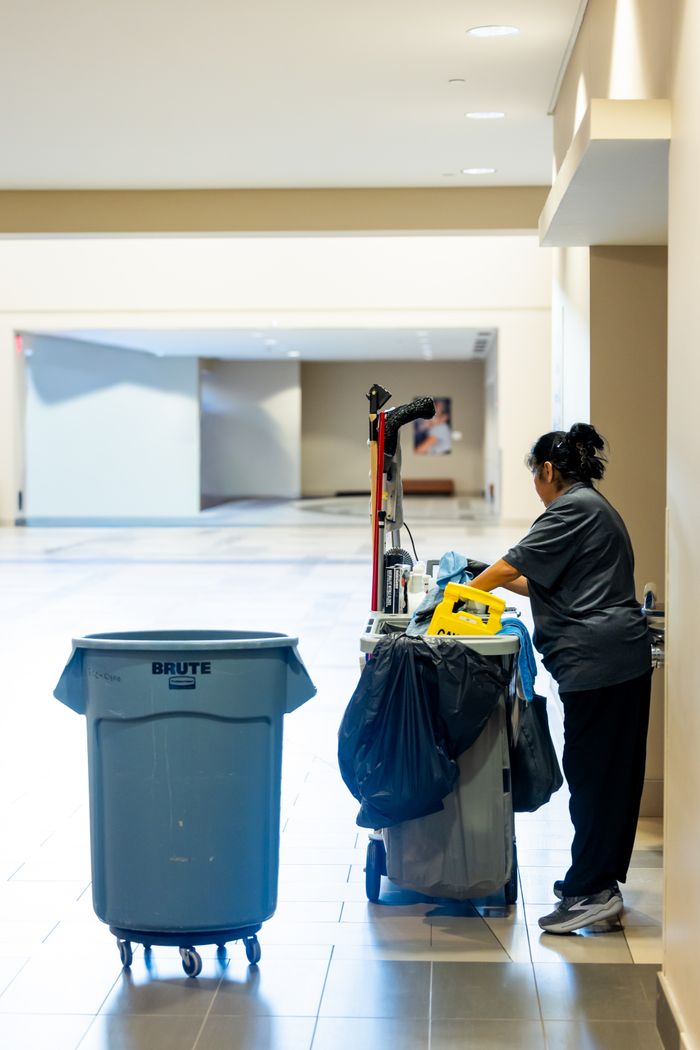 Mastering the First Impression: Your intriguing post title goes here A janitorial worker pushes a cleaning cart in a spacious indoor hallway.